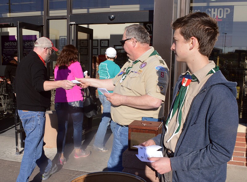 Paul Scheppers, Scoutmaster for Boy Scouts Troop 12, hands out information regarding their food drive for the Samaritan Center at Hy-Vee on Friday, March 2, 2018. Helping Scheppers is August Grantham.