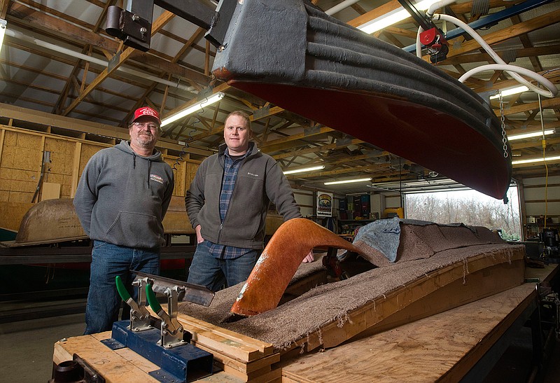 William Davis (left) and brother Louis Shaw of Two Brothers Canoes pose for a photo Feb. 23 next to one of the vacuum molds at their facility near Rogers.