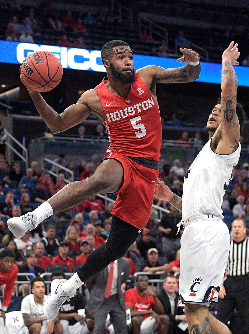 Houston guard Corey Davis Jr. passes the ball in front of Cincinnati guard Jarron Cumberland, right, during the first half of the American Athletic Conference championship Sunday in Orlando, Fla.  Houston lost, 56-55, but drew the sixth seed in the NCAA Tournament and will play San Diego State in the first round.