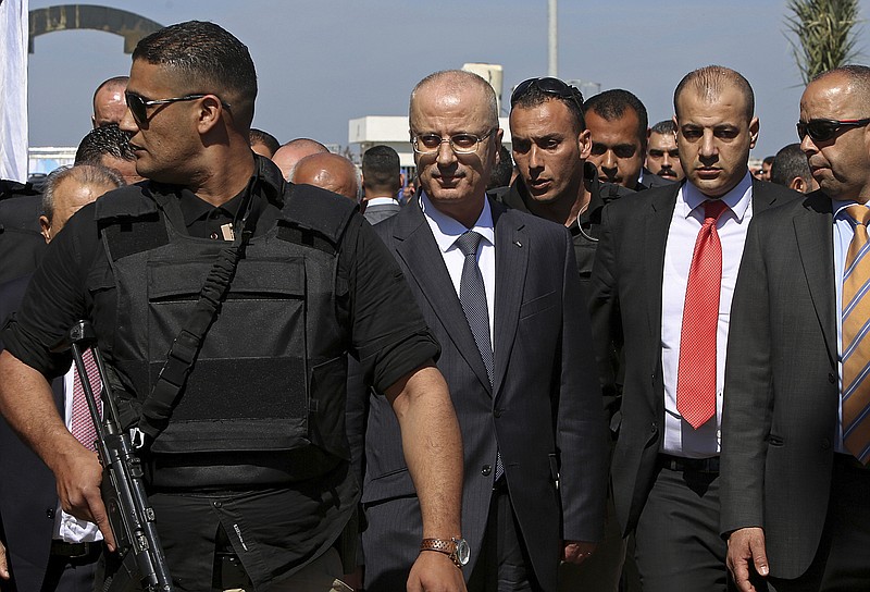 Palestinian Prime Minister Rami Hamdallah, center left, is surrounded by body guards as he arrives for the opening ceremony of a long-awaited sewage plant project, east of Jebaliya, in the northern Gaza strip, Tuesday, March 13, 2018. An explosion occurred as the convoy of the prime minister entered Gaza through the Erez crossing with Israel. The Fatah party of the prime minister called the explosion an assassination attempt and blamed Gaza militants. (AP Photo/Adel Hana)