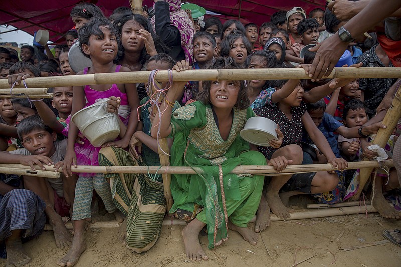 FILE - In this Saturday, Oct. 21, 2017, file photo, Rohingya Muslim children wait for food handouts distributed by a Turkish aid agency at Thaingkhali refugee camp, Bangladesh. Myanmar's government has rejected two reports presented to the U.N. Human Rights Council that concluded it committed extreme human rights violations, probably amounting to crimes under international law, in its repression of several minority groups. (AP Photo/Dar Yasin, File)