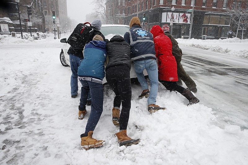 People push a stranded taxi during a snowstorm, Tuesday, March 13, 2018, in Boston.  The third major nor’easter in two weeks slammed New England on Tuesday, bringing blizzard conditions and more than a foot of snow to some communities.   (AP Photo/Michael Dwyer)