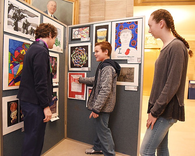 Russellville Elementary School art teacher Amy Potts, left, visits with two of her award-winning students, Colten Koenigsfeld, middle, and Paige Randolph on Monday at the Capitol as they view their work in a Capitol Rotunda display. 