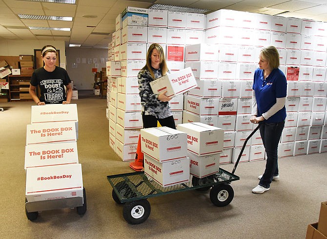 Ashley Stiefermann, left, Nikki Bateman and Lisa Otto, all Missouri River Regional Library employees, move boxes of books for the annual sale that begins Wednesday at the Knights of Columbus Hall in St. Martins. More than 3,300 boxes of books will be delivered to the hall to be displayed for the public to purchase. Buyers from several states will be on hand to refill their stock and to look for that niche or unique book to put in their shop. The sale runs through Saturday.