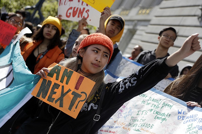 Sandy Shieh, center, a student at San Francisco's Lincoln High School holds a sign as she listens to speakers during a rally and march against gun violence at the Civic Center Plaza Wednesday, March 14, 2018, in San Francisco, one month after a deadly shooting inside a high school in Parkland, Fla. (AP Photo/Marcio Jose Sanchez)