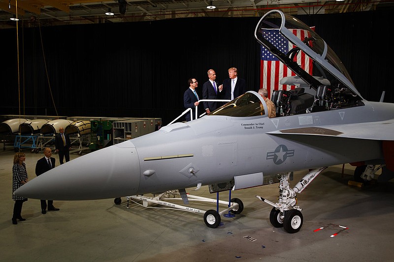 Treasury Secretary Steve Mnuchin and Boeing CEO Dennis Muilenburg listen to President Donald Trump talk with Boeing test pilot Steve Schmidt during a tour of fighter aircraft at the Boeing Company, Wednesday, March 14, 2018, in St. Louis.