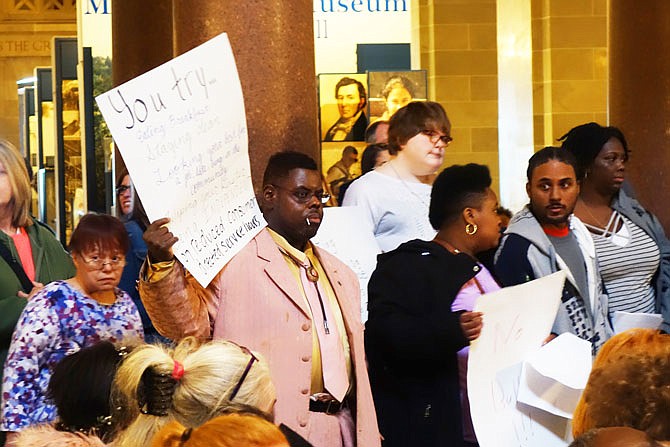 A disability rights activist holds a sign protesting the cutting of consumer-directed service hours during Wednesday's Disability Rights Legislative Day at the Capitol. Last year, state budget cuts led to the capping of consumer-directed care at 60 percent of previous hours, meaning that people trying to live independently with disabilities have less access to help.