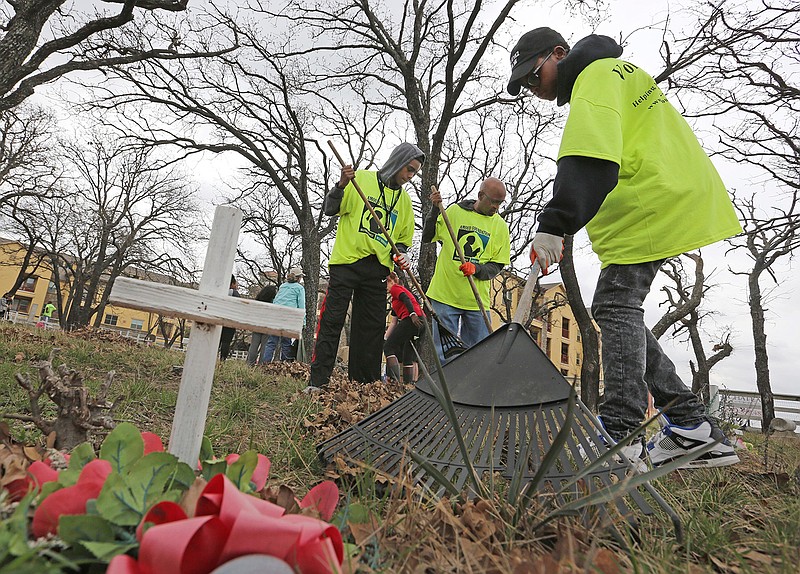 In a Saturday, March 10, 2018 photo, volunteers work to clean up Shelton's Bear Creek Cemetery in Irving, Texas. The cemetery was discovered in 1995 and a book was written about the site. The cemetery gained historical landmark status in 2000. (Louis DeLuca/The Dallas Morning News via AP)