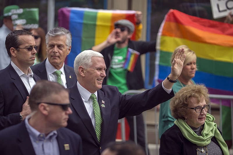 Vice President Mike Pence and his mother Nancy Pence Fritsch, right, wave while walking in the St. Patrick's Day parade Saturday, March 17, 2018, in Savannah, Ga.  Crowds behind barricades across the street cheered and chanted "U-S-A" as Pence waved and gave a thumbs up sign. There were also a few protesters who followed Pence throughout the parade. (AP Photo/Stephen B. Morton)