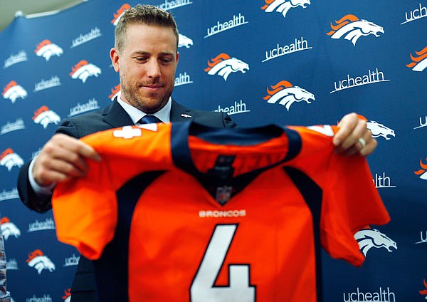 Case Keenum looks at his new jersey during a news conference Friday introducing him as the starting quarterback of the Broncos in Englewood, Colo.