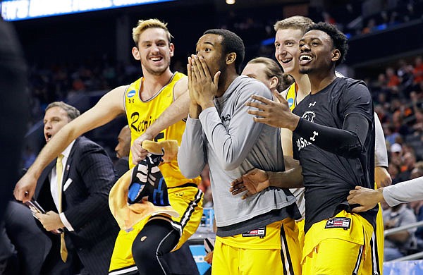 UMBC players celebrate a teammate's basket during the second half of Friday night's game against Virginia in Charlotte, N.C.