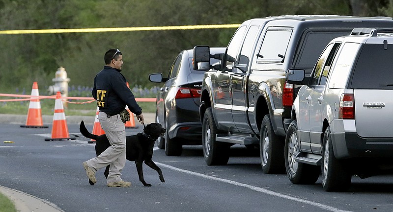 An agent the Bureau of Alcohol, Tobacco, Firearms and Explosives works with his dog near the site of Sunday's explosion, Monday, March 19, 2018, in Austin, Texas. Fear escalated across Austin on Monday after the fourth bombing this month — this time, a blast that was triggered by a tripwire and demonstrated what police said was a "higher level of sophistication" than the package bombs used in the previous attacks.  (AP Photo/Eric Gay)