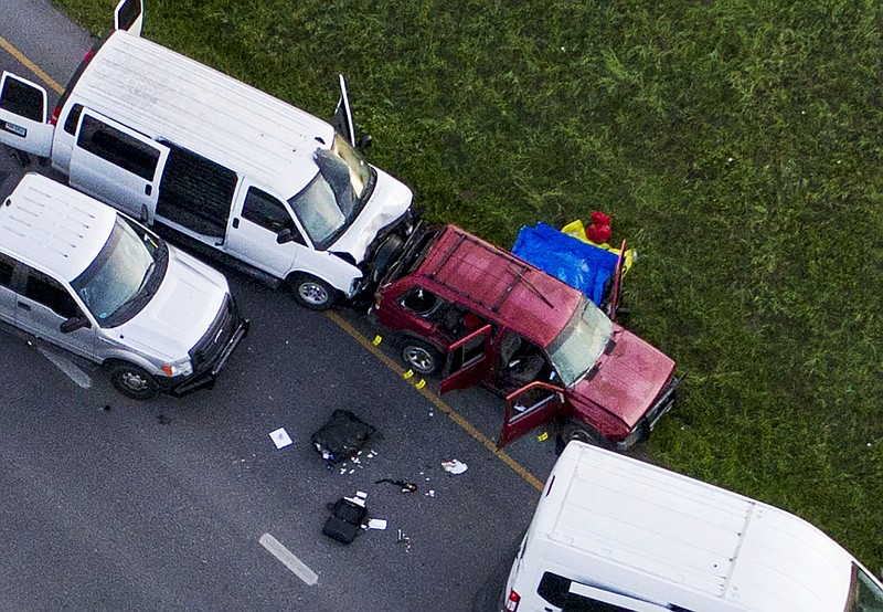 Officials investigate near a vehicle, center, where a suspect in the deadly bombings that terrorized Austin blew himself up as authorities closed in on him, in Round Rock, Texas, Wednesday, March 21, 2018. (Jay Janner/Austin American-Statesman via AP)