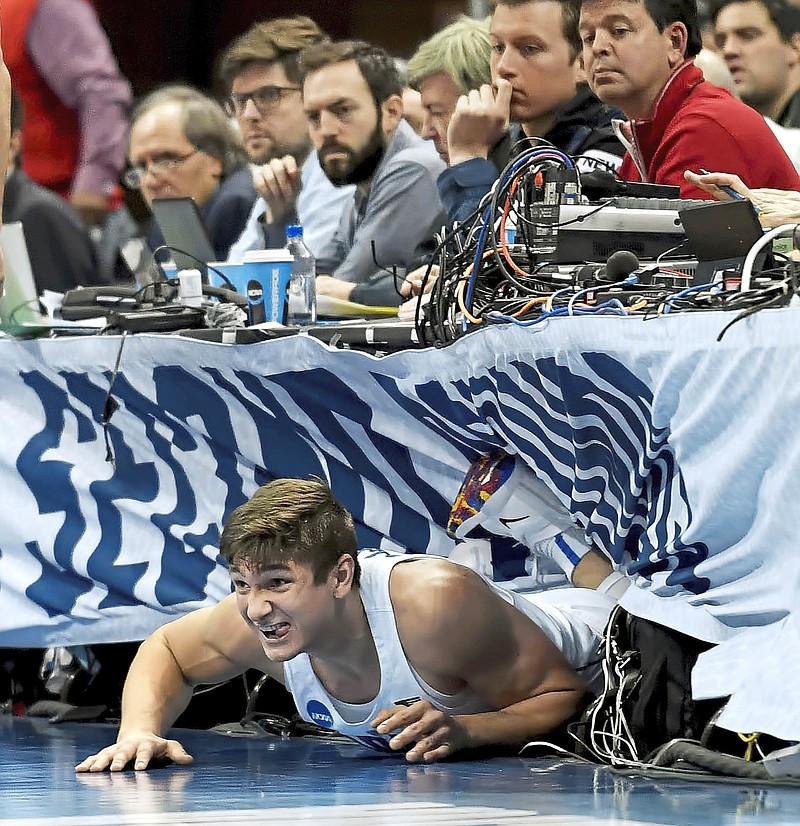 Duke's Grayson Allen ends up under the media row after diving for a loose ball against Rhode Island in the first half of the second round of the NCAA tournament Saturday, March 17, 2018, in Pittsburgh, Pa. (Matt Freed/Post-Gazette via AP)