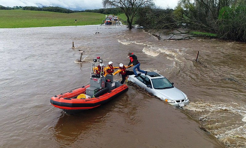 This drone photo from video provided by the California Governor's Office of Emergency Services shows firefighters from the Folsom, Calif., Fire Department rescuing a motorist whose car became stuck as a flash flood washed over a road near Folsom Thursday, March 22, 2018. A powerful storm spread more rain across California on Thursday, swelling rivers, flooding streets and causing some mud and rock slides but, so far, sparing communities a repeat of the disastrous debris flows that hit during a downpour early this year. (Kelly B. Huston/California Governor's Office of Emergency Services via AP)