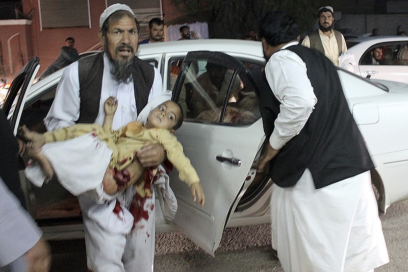 A man carries a wounded boy in a hospital, after a car bombing outside a sports stadium in Lashkargah, capital city of southern Helmand province, Afghanistan, Friday, March 23, 2018. Provincial chief of police Abdul Ghafar Safi said the blast was carried out by a suicide bomber and that the target was civilians. (AP Photo/Abdul Khaliq)