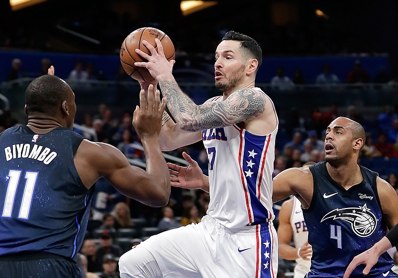 Philadelphia 76ers' JJ Redick, center, looks to pass the ball as he gets between Orlando Magic's Bismack Biyombo (11) and Arron Afflalo (4) during the first half of an NBA basketball game, Thursday, March 22, 2018, in Orlando, Fla. (AP Photo/John Raoux)
