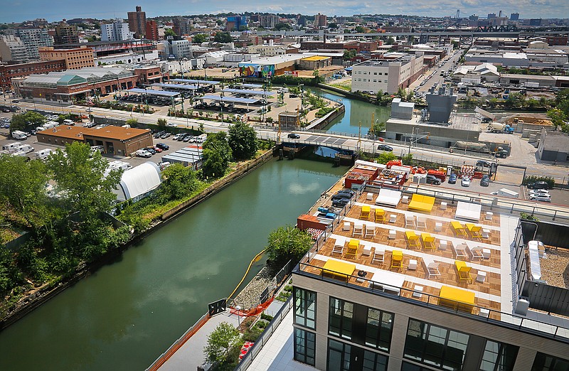 This July 5, 2016, file photo shows a view of Brooklyn's Gowanus Canal and the the rooftop lounge of the new 365 Bond Street apartments, right, a new development from Lightstone, in New York. A house with a fabulous view can be hard for a homebuyer to resist. But seeing the mountains, water or city lights from the comfort of home comes at a price. (AP Photo/Bebeto Matthews, File)