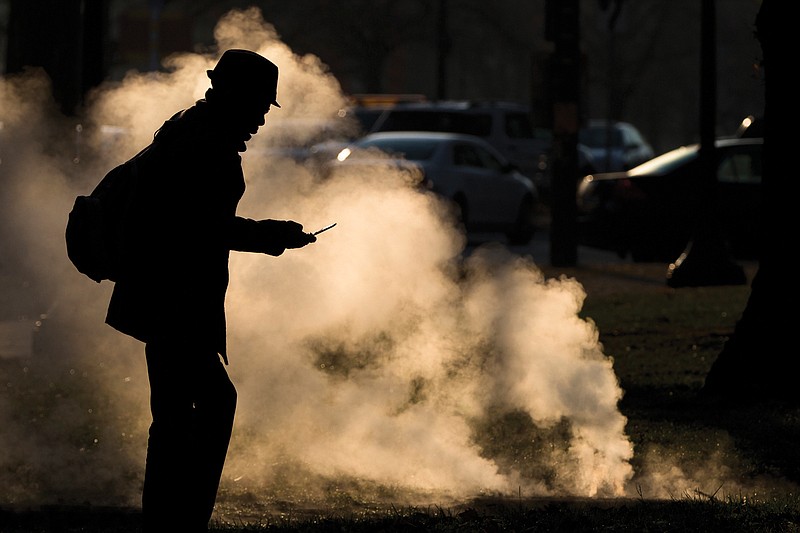 In this Nov. 30, 2012 file photo, a pedestrian looks at his phone near steam vented from a grate near the Philadelphia Museum of Art on a cold morning in Philadelphia. Every time a person shops online or at a store, loyalty cards linked to phone numbers or email addresses can be linked to other databases that may have location data, home addresses and more. Voting records, job history, credit scores (remember the Equifax hack?) are constantly mixed, matched and traded by companies in ways regulators haven't caught up with. (AP Photo/Matt Rourke, File)