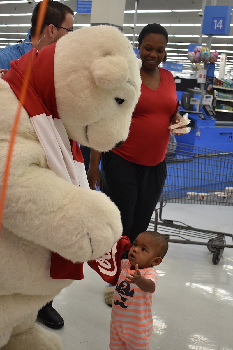 Zay'Aire, 1, of Texarkana, Texas, visits with the Coca-Cola polar bear during the grand opening of the online grocery pickup service at the Texarkana, Ark., Walmart.