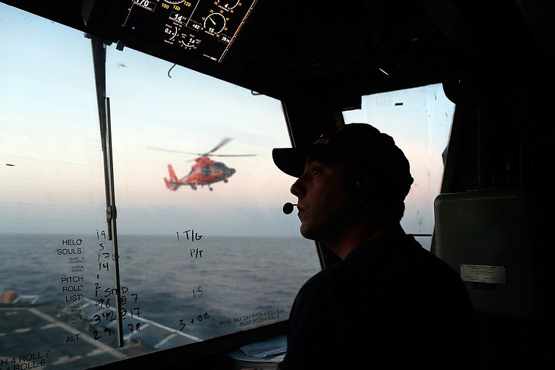 In this March 2, 2017 photo, an unidentified U.S. Coast Guardsman communicates with the pilot of a helicopter during take-off and landing exercises on the U.S. Coast Guard cutter Stratton in the eastern Pacific Ocean. The U.S. Coast Guard is teaming up with the Mexican and Colombian navies off South America's Pacific coast to go after seafaring smugglers, opening a new front in the drug war. (AP Photo/Dario Lopez-Mills, File)