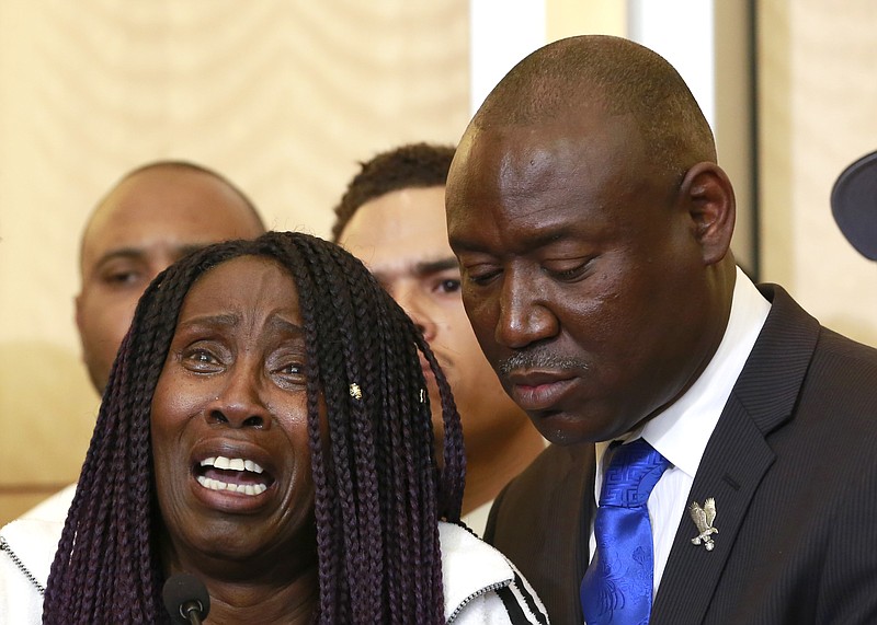 In this Monday March 26, 2018, file photo, attorney Benjamin Crump, right, stands alongside Sequita Thompson as she breaks into tears while talking about the fatal police shooting of her grandson Stephon Clark during a news conference, in Sacramento, Calif. Over the years, Crump has represented the relatives of other unarmed black men fatally shot by police in other parts of the country. (AP Photo/Rich Pedroncelli, File)