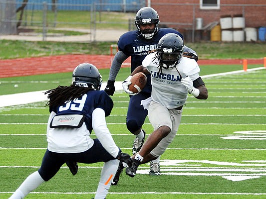 Kimbo Ferguson of Lincoln carries the ball as Jordan Reddick looks to make a tackle during a scrimmage Saturday afternoon at Dwight T. Reed Stadium. Lincoln will host its spring game Saturday, April 14.