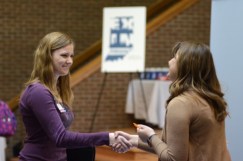 FILE- In this March 14, 2018, file photo, Indiana Wesleyan University senior Courtney Kingma, left, thanks Jennie Hehe, community resource manager for Tangram, for talking with her during the Experience Indiana job fair event in the student center at IWU in Marion, Ind. On Friday, April 6, the U.S. government issues the March jobs report. (Jeff Morehead/The Chronicle-Tribune via AP, File)