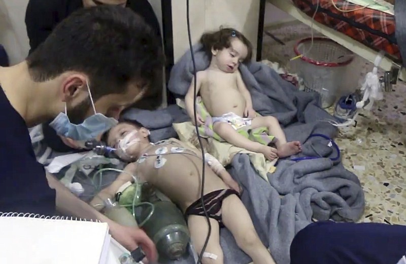 This image made from video released by the Syrian Civil Defense White Helmets, which has been authenticated based on its contents and other AP reporting, shows medical workers treating toddlers following an alleged poison gas attack in the opposition-held town of Douma, in eastern Ghouta, near Damascus, Syria, Sunday, April. 8, 2018. The Civil Defense said patients were having difficulty breathing and burning in their eyes. Syrian opposition activists and rescuers said Sunday that a poison gas attack on a rebel-held town near the capital. The Syrian government denied the allegations, which could not be independently verified. (Syrian Civil Defense White Helmets via AP)