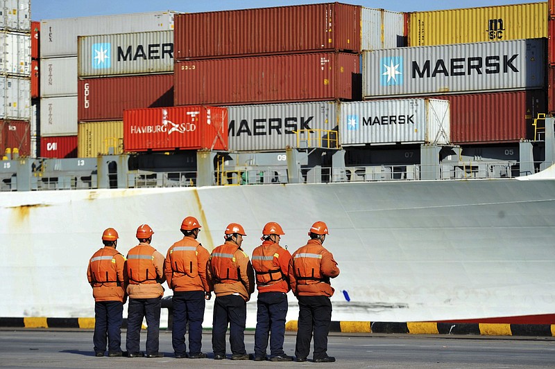 Chinese workers stand in front of a loaded cargo ship docked at a port in Qingdao in east China's Shandong province, Sunday, April 8, 2018. Amid falling markets, President Donald Trump's new economic adviser, Larry Kudlow, says there is no trade war between the U.S. and China. Another administration official, Treasury Secretary Steve Mnuchin, takes a different tack, saying he's "cautiously optimistic" that before any threatened tariffs go into place the two nations will reach an agreement. Global financial markets have fallen sharply as the world's two biggest economies square off. (Chinatopix via AP)