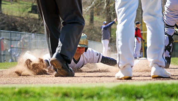 Alex Buschjost of Helias dives safely across home plate during the first inning of Saturday's third-place game of the Capital City Invitational against Jefferson City at Vivion Field.