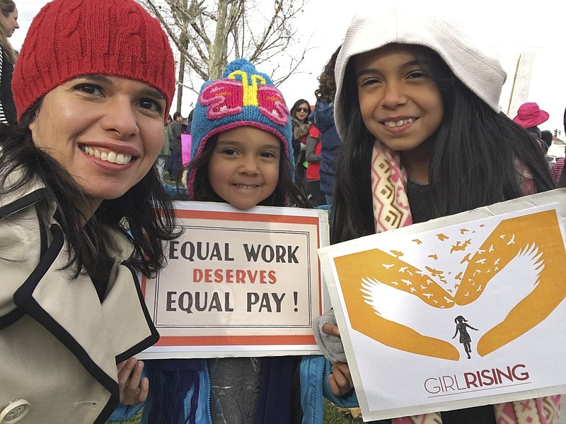 In this Jan. 21, 2017 photo provided by Aileen Rizo,  Rizo, along with her daughters Diana Acosta, 10, center, and Vivan Acosta, 6, right, attend the national Women's March in Fresno, Calif. Relying on women's previous salaries to determine their incomes at new jobs perpetuates longstanding disparities in the wages of men and women and is illegal when it results in higher pay for men, a federal appeals court ruled on Monday, April 9, 2018, in a novel opinion that aims to address the "financial exploitation of working women." The unanimous ruling by an 11-judge panel of the 9th U.S. Circuit Court of Appeals came in the case of a California school employee who learned over lunch with colleagues in 2012 that she made thousands less than her male counterparts. Aileen Rizo took a job as a math consultant in Fresno County in 2009 after working for several years in Arizona. (Aileen Rizo via AP)