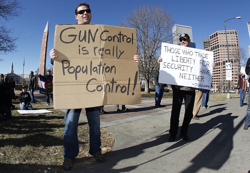 FILE- This Jan. 9, 2013 file photo shows Craig Larson, right, of Fort Collins, Colo., and another protester who refused to identify himself waving signs during a pro-gun rally in a park across from the State Capitol in Denver. Organizers are encouraging gun rights supporters to bring unloaded weapons to rallies at state capitols across the U.S. this weekend of April 14, 2018, to counter a recent wave of student-led protests against gun violence. (AP Photo/David Zalubowski, File)