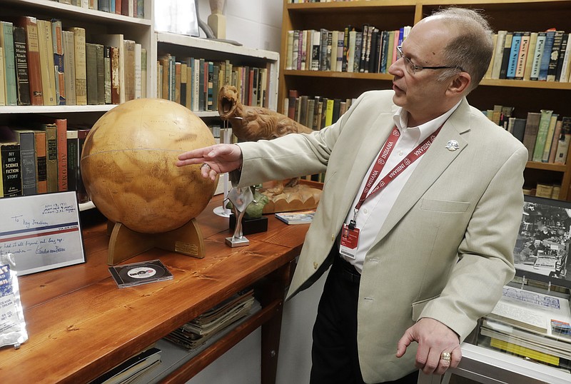 In this Thursday, April 12, 2018, photo, Center for Ray Bradbury Studies director Jonathan Eller points out the location of Gale Crater on the Mars globe, in Indianapolis. The globe presented to Ray Bradbury for his support of NASA's Mariner 9 Mars orbital mission in 1971. (AP Photo/Darron Cummings)
