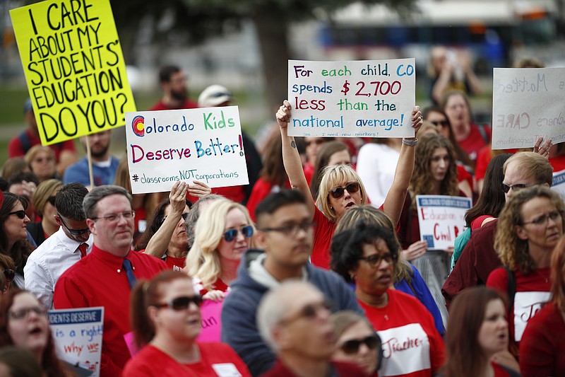 Teachers hold placards during a rally outside the state Capitol, Monday, April 16, 2018, in Denver. Teachers from around the state were on hand to demand better salaries as lawmakers under the dome were set to debate a pension reform measure to cut retirement benefits as well as take-home pay. (AP Photo/David Zalubowski)