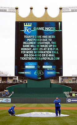 Grounds crew workers cover the pitcher's mound after Sunday's game between the Royals and the Angels at Kauffman Stadium was postponed due to inclement weather.