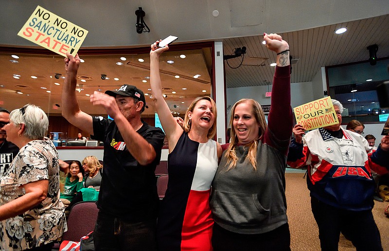 David Hernandez, left, Genevieve Peters, center, and Jennifer Martinez celebrate after the Orange County Board of Supervisors voted to join the U.S. Department of Justice lawsuit against the State of California's sanctuary cities law (SB54) during their meeting March 27 in Santa Ana, Calif. More local governments in California are resisting the state's efforts to resist the Trump administration's immigration crackdown, and political experts see politics at play as Republicans try to fire up voters in a state where the GOP has grown weak.