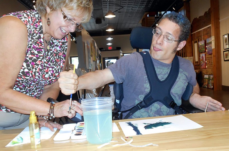 <p>Submitted</p><p>Frances Fortner, an AEC staff member, assists AEC participant Larry Schneider with a painting project at the Art House. Other field trips included Warm Springs Ranch in Boonville and Where Pigs Fly petting zoo in Linn.</p>