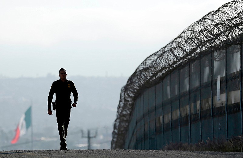 FILE - In this June 22, 2016 file photo, Border Patrol agent Eduardo Olmos walks near the secondary fence separating Tijuana, Mexico, background, and San Diego in San Diego. California Gov. Jerry Brown agreed Wednesday, April 11, 2018, to deploy 400 National Guard troops at President Donald Trump's request, but not all will head to the U.S.-Mexico border as Trump wants and none will enforce federal immigration enforcement. (AP Photo/Gregory Bull, File)