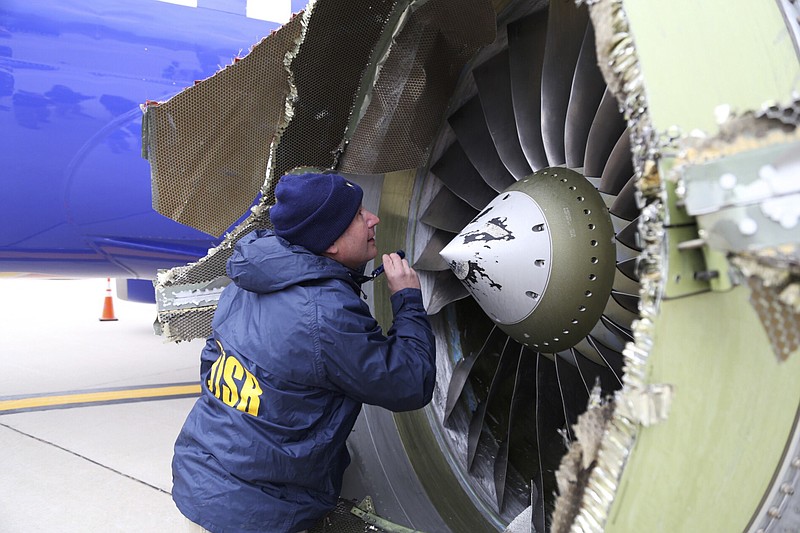 In this Tuesday, April 17, 2018 photo, a National Transportation Safety Board investigator examines damage to the engine of the Southwest Airlines plane that made an emergency landing at Philadelphia International Airport in Philadelphia. A preliminary examination of the blown jet engine of the Southwest Airlines plane that set off a terrifying chain of events and left a businesswoman hanging half outside a shattered window showed evidence of "metal fatigue," according to the National Transportation Safety Board. (NTSB via AP)