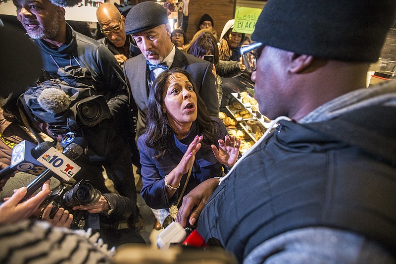 Camille Hymes, center, regional vice president of Mid-Atlantic operations at Starbucks Coffee Company, speaks with Asa Khalif, of Black Lives Matter, right, after protesters entered the coffee shop, Sunday, April 15, 2018, demanding the firing of the manager who called police resulting in the arrest of two black men on Thursday. The arrests were captured on video that quickly gained traction on social media. (Mark Bryant/The Philadelphia Inquirer via AP)