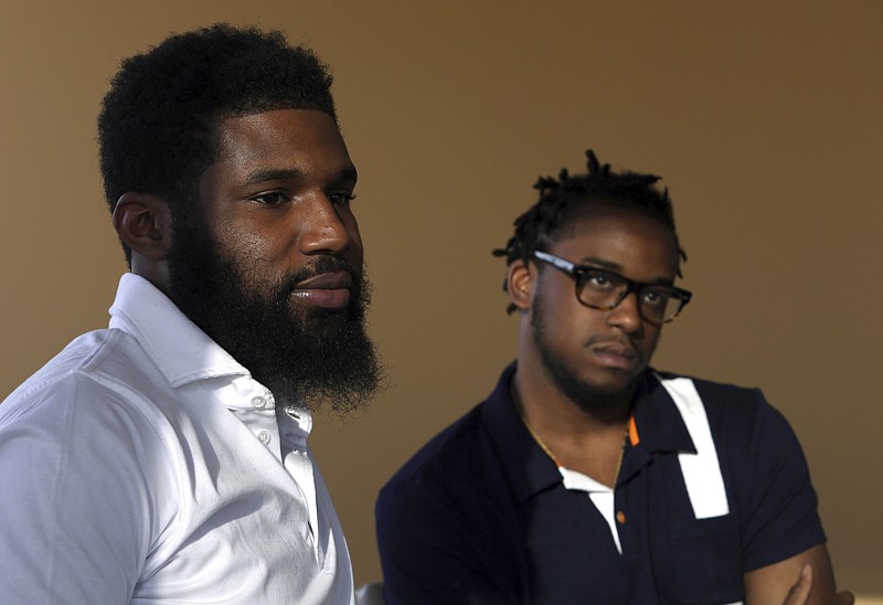 In this Wednesday, April 18, 2018 photo, Rashon Nelson, left, and Donte Robinson, right, listen to a reporter's question during an interview with The Associated Press in Philadelphia. Their arrests at a local Starbucks quickly became a viral video and galvanized people around the country who saw the incident as modern-day racism. In the week since, Nelson and Robinson have met with Starbucks CEO Kevin Johnson and are pushing for lasting changes to ensure that what happened to them doesn't happen to future patrons. (AP Photo/Jacqueline Larma)