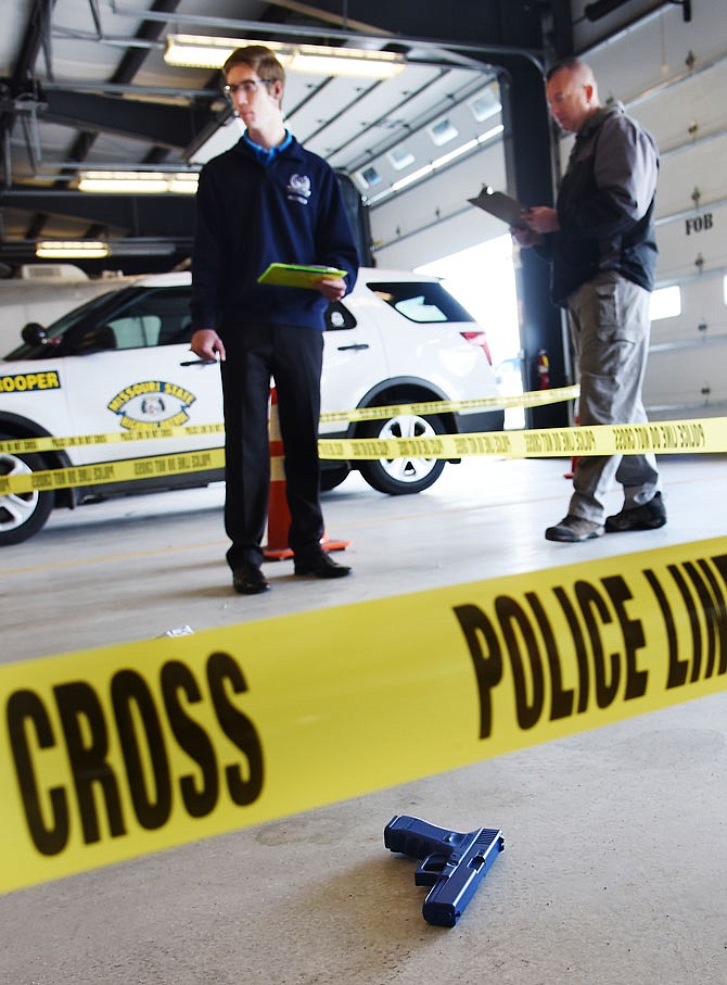 Andrew Hurley takes notes at a crime scene setup Thursday, April 19, 2018. He was one of nearly 100 students from across the state to attend training at the Missouri Highway Patrol training facility on the grounds of the Ike Skelton Training Site. Sgt. Erik Eidson of the patrol is pictured with Hurley, who attends Herndon Career Center in Raytown.