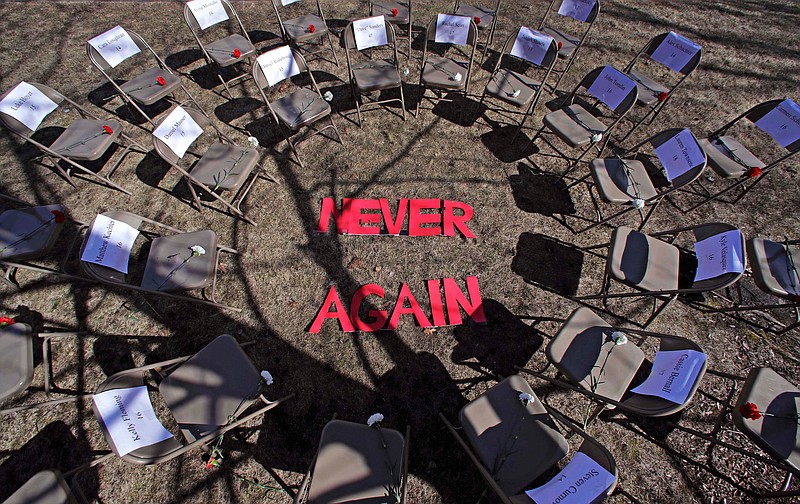 Two rings of chairs encircle the words "NEVER AGAIN" in a silent protest on the 19th anniversary of the Columbine High School shooting outside Trinity High School in Manchester, N.H., Friday, April 20, 2018. The inner ring chairs have names of the Columbine victims, the outer ring chairs have names of the Parkland High School shooting victims. (AP Photo/Charles Krupa)