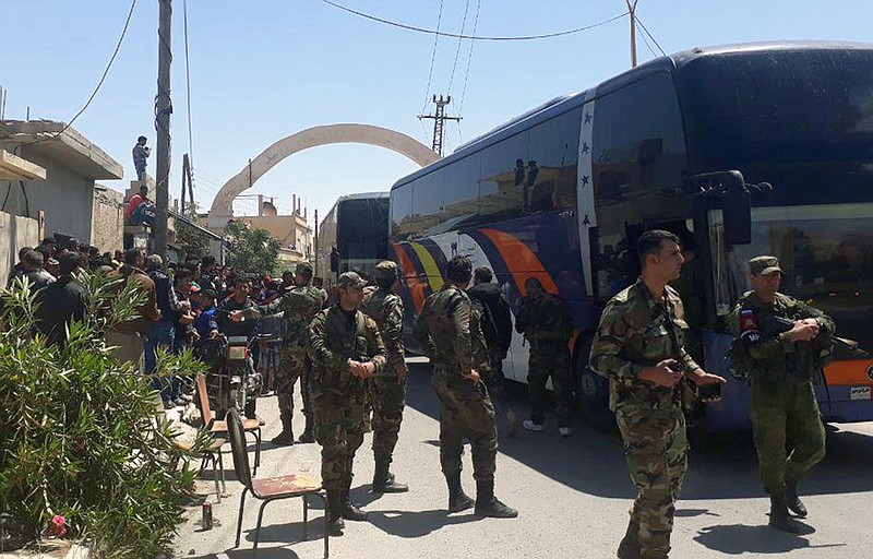 This photo released by the Syrian official news agency SANA, shows Syrian government forces overseeing the evacuation by bus of rebels and their family from the towns of Ruhaiba in the eastern Qalamoun region in the Damascus countryside, Syria, Saturday, April 21, 2018. Syrian state media says several buses have left the towns of Ruhaiba, Jayroud, and al-Nasriya carrying hundreds of rebels and their families to opposition territory in north Syria. (SANA via AP)