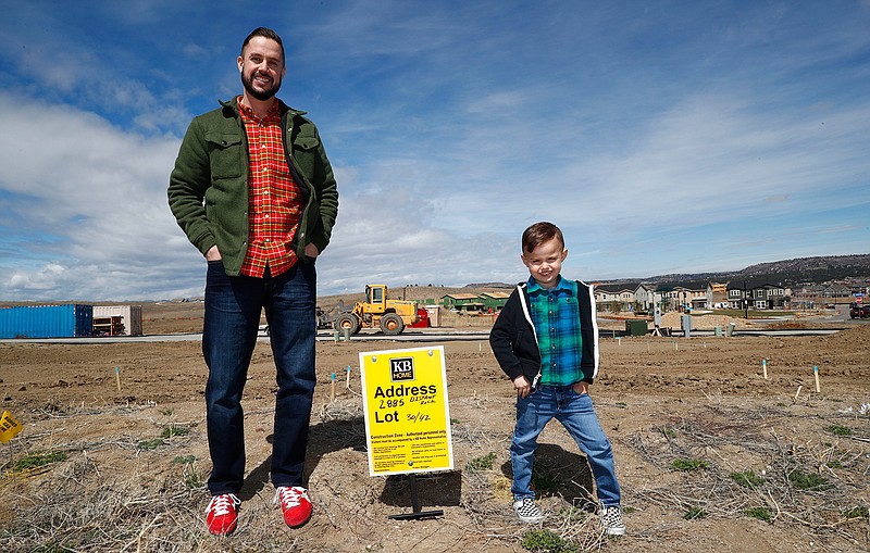 In this Saturday, April 7, 2018, photo, Chad Zolman, left, joins his 5-year-old son, Quinten, in standing at the site of their yet-to-be-constructed new home in Castle Rock, Colo. A tight housing market, further complicated by climbing interest rates and rising prices, has forced buyers such as Zolman to move farther out of the Denver metropolitan area. Zolman eventually bought a newly built, three-bedroom townhome for $370,000. (AP Photo/David Zalubowski)