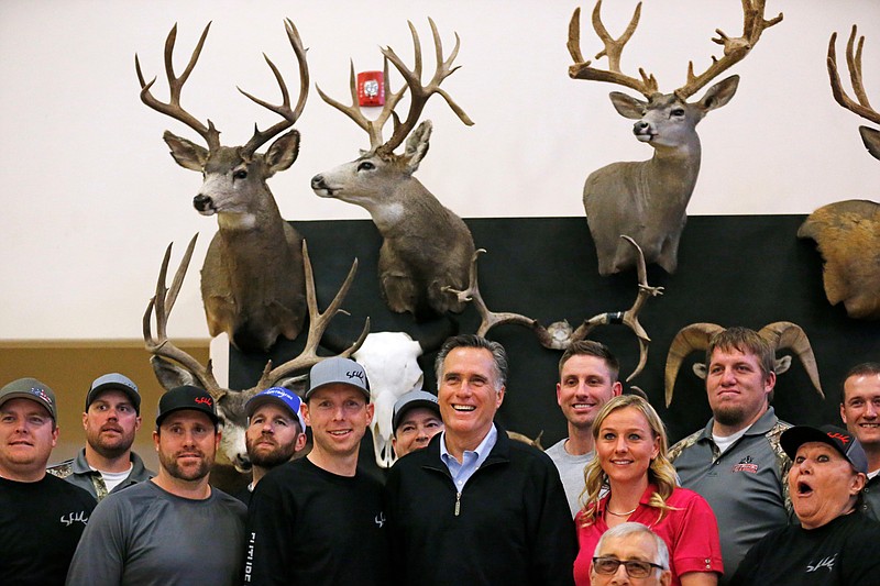 In this Friday, March 2, 2018 photo, Mitt Romney poses with a group at the Sportsmen for Fish and Wildlife Banquet during a campaign stop, in Blanding, Utah. Romney is gearing up for arguably the biggest challenge of his Senate campaign: A Utah Republican party convention where he'll have to face down nearly a dozen contenders in front of a far-right-leaning audience. (AP Photo/Rick Bowmer, File)