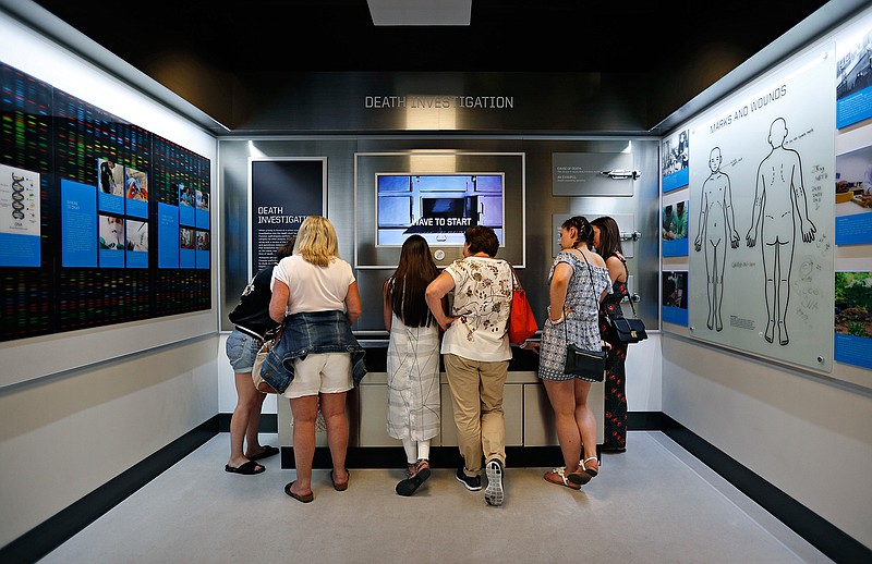 In this April 12, 2018, photo, people look at an interactive exhibit at the Crime Lab Experience in the Mob Museum in Las Vegas. For years the museum has showcased the area's storied past in organized crime, but visitors can now also enjoy a speakeasy, a use of deadly force training experience, and an interactive crime lab exhibit. (AP Photo/John Locher)