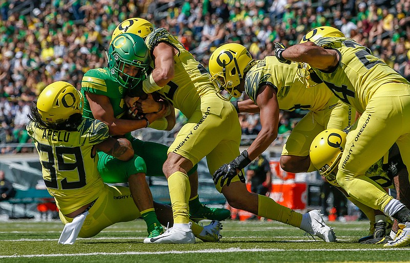 Running back Travis Dye is stopped by Kaulana Apelu, Troy Dye, Thomas Graham Jr. and Keith Simms during the Oregon spring college football game Saturday, April 21, 2018, in Eugene, Ore. (Andy Nelson/The Register-Guard via AP)