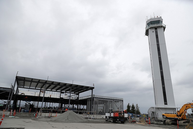 In this April 11, 2018 photo, construction of a privately-run commercial U.S. airport terminal takes place near the control tower at Paine Field in Everett, Wash. The public-private partnership contrasts with the majority of about 500 commercial airports across the U.S., where local governments own and operate the facilities. The terminal has commitments from Alaska Airlines, Southwest Airlines and United Airlines for up to 24 daily flights, mostly to destinations in the West and Midwest. (AP Photo/Ted S. Warren)
